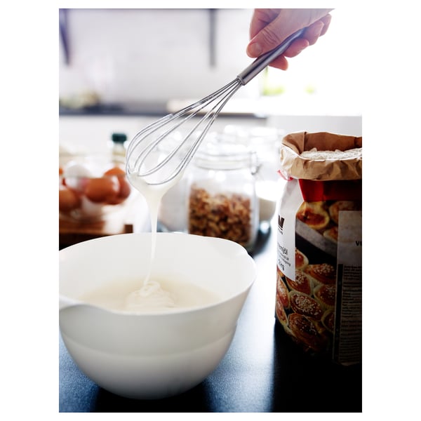 Hand mixing in bowl, whisk beside baked goods.