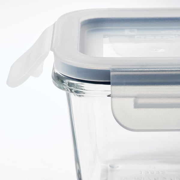 Clear glass food container with transparent lid, white handle, and silicone seal.