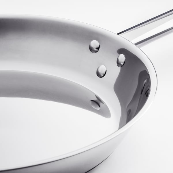 Stainless steel frying pan with smooth, even surface and sturdy riveted handle.