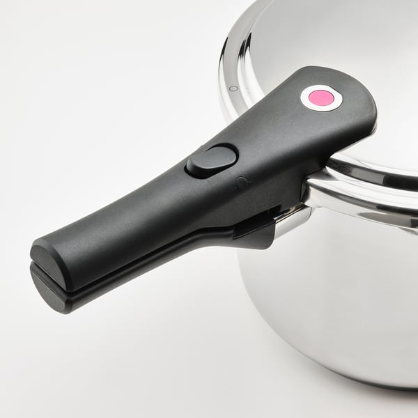 Black handle of a stainless-steel pressure cooker with a red button and safety valve, showcasing durability and ease of use.