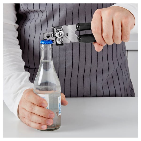Person using ikea can and bottle opener, efficiently opening a bottle with blue cap.