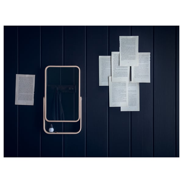 Dark wall with wooden-framed mirror. Papers attached around it.