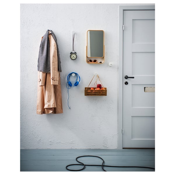 Tidy entrance with coat, headphones, clock, mirror, apples by door.