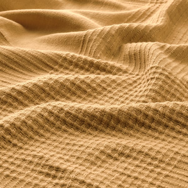 Soft, textured beige cotton blanket, warm and inviting.