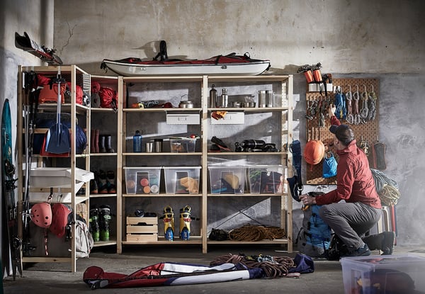 A person organising sports gear in a room with IVAR storage shelves and pegboards.
