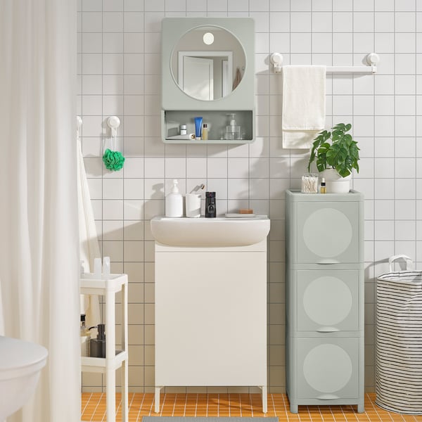 Modern bathroom with IVÖSJÖN white vanity; mirror, green shelves, clean lines.