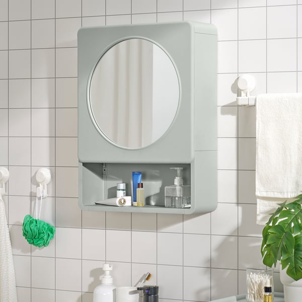 Green IVÖSJÖN bathroom cabinet with mirror, open & closed storage, white tiles, towels, sponge.