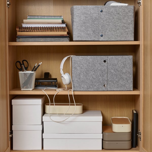 Organised shelves with felt boxes, stationery, and headphones for storage and accessibility.