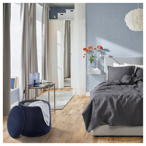 Bedroom with JÄRRESTAD pouffe, storing items. Dark bedding, mirror, wooden floor, modern decor.