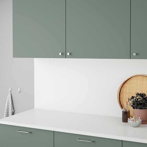 Modern kitchen featuring sea foam green cabinetry with white countertop. Decor includes a hanging towel and a plant.