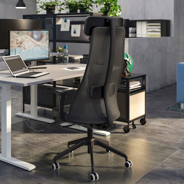 Modern office with black mesh chair, desk, laptop, monitor, and shelves.