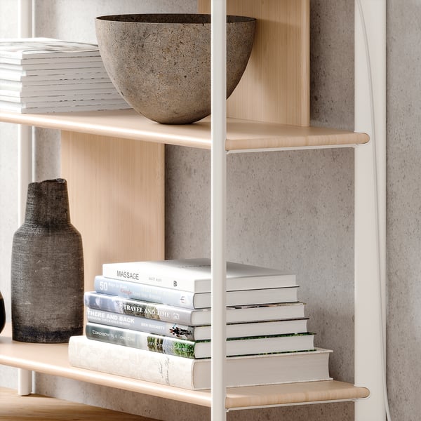 Modern bookcase with light wood shelves, white metal frame, displaying bowls and books.
