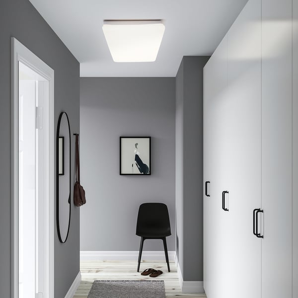 Modern entryway with JETSTRÖM light panel, white closet, black chair, mirror, and doormat.