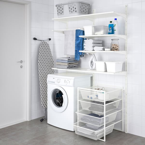 Small, white, metal JONAXEL storage shelves hold laundry items. A washing machine sits beneath.