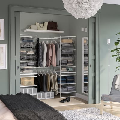 Modern walk-in closet with JONAXEL storage, seating, dark rug, light walls.