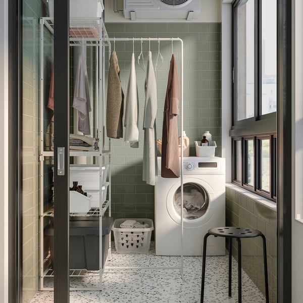 Modern laundry room with white storage, green tiles, and natural light.