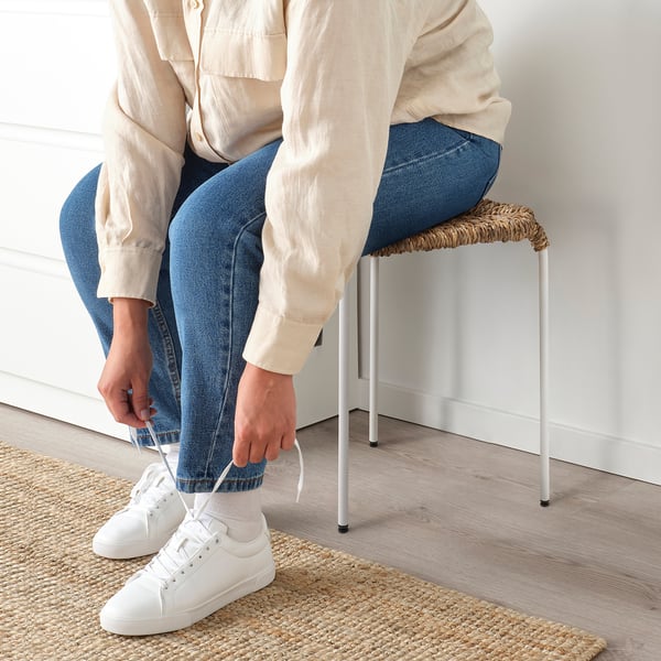 Person tying white trainers on stools.
