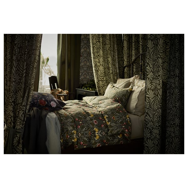 Bedroom with floral patterned bedding, dark curtains, and chair. Duvet cover in earthy tones with floral designs.