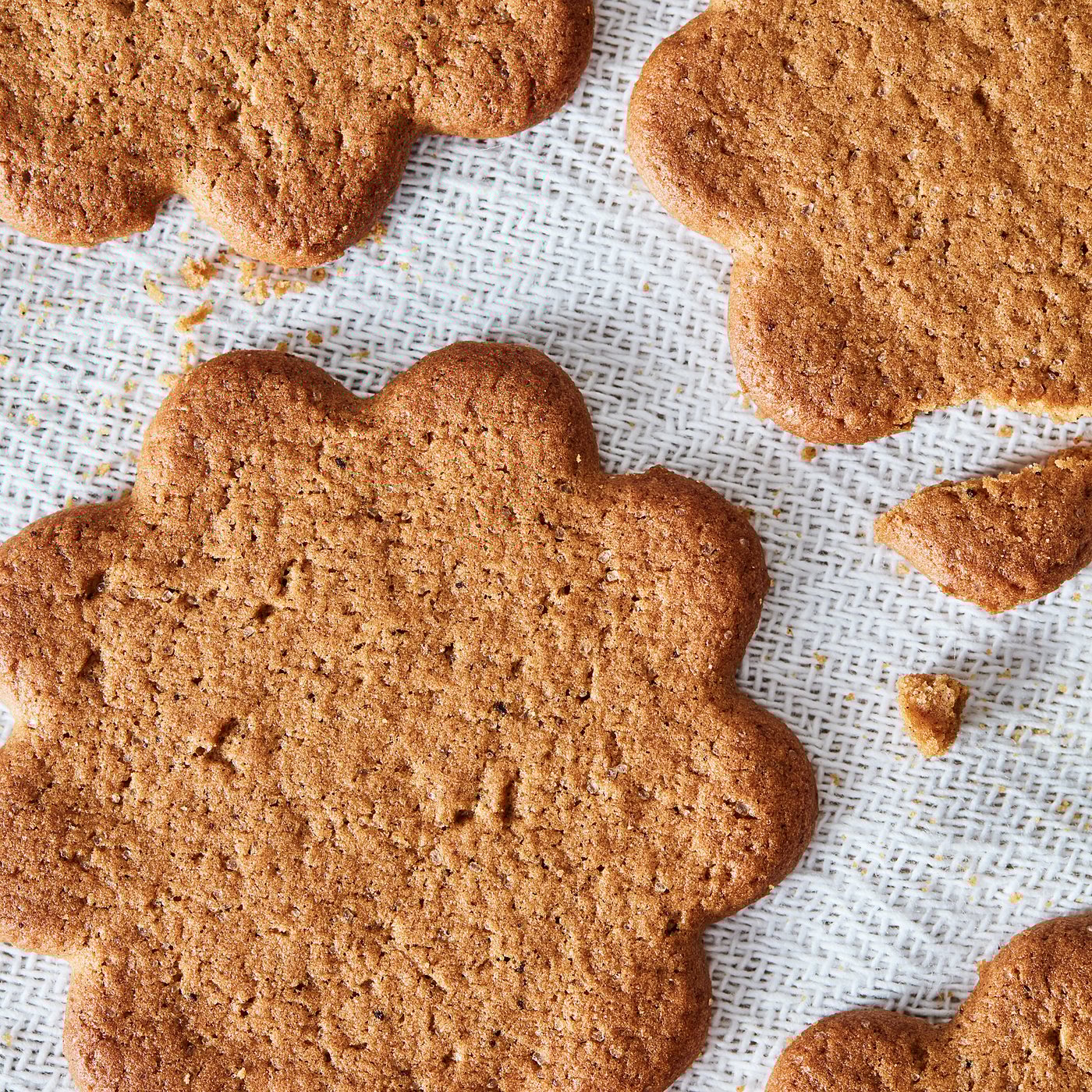 Six heart-shaped ginger cookies, golden-brown, on a light, textured cloth.
