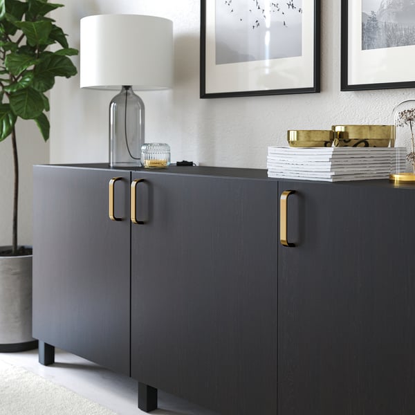 Modern cabinet with gold handles and a table lamp on top. The handles provide a good grip for easy opening.