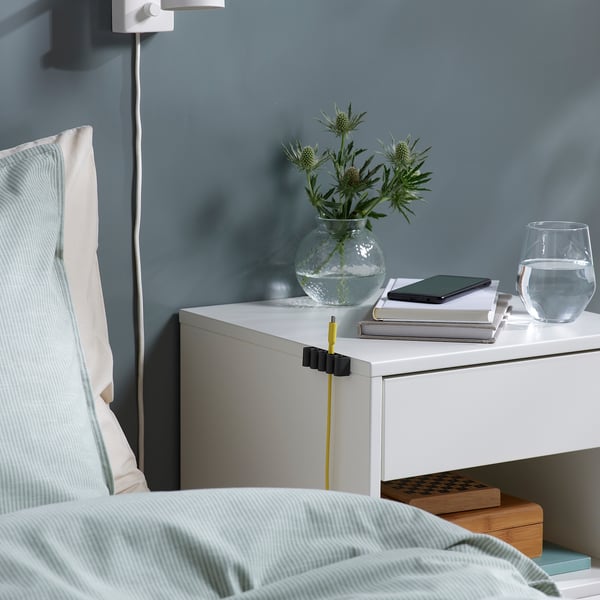 Bedside table with organised cables using KALKSTUFF holders, keeping cords tidy and accessible.