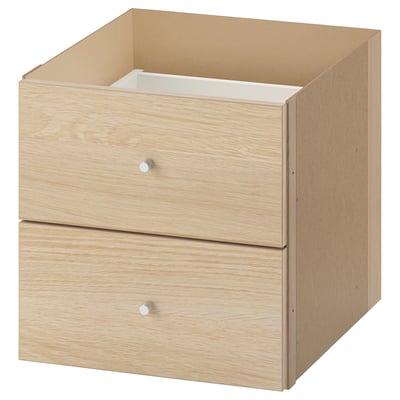 An ikea KALLAX unit with two drawers in light oak finish. It a simple, rectangular design with wooden texture and silver drawer knobs.