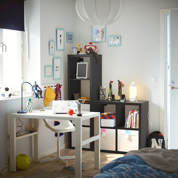 A kids room with a white KALLAX storage unit, filled with colourful boxes and awards.