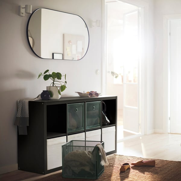 KALLAX black & white storage unit with mesh bins, plant, mirror; stylish, practical hall setup.