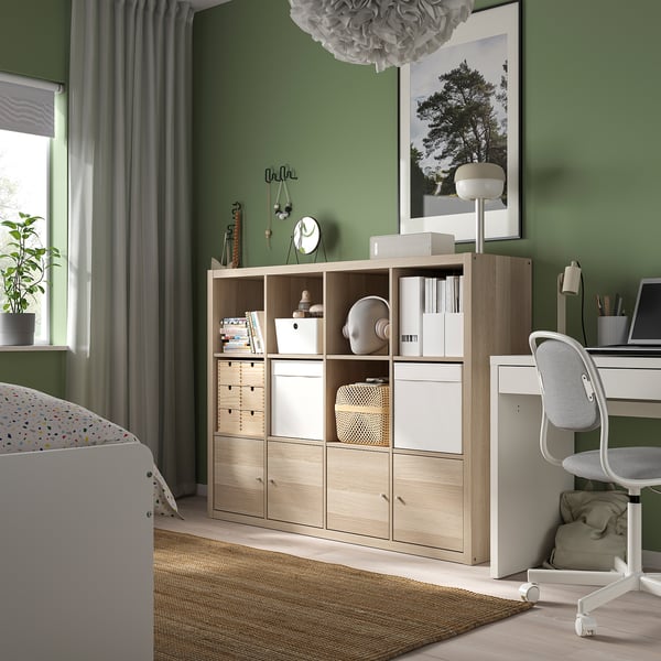 KALLAX shelving with mixed items, desk chair by green window.