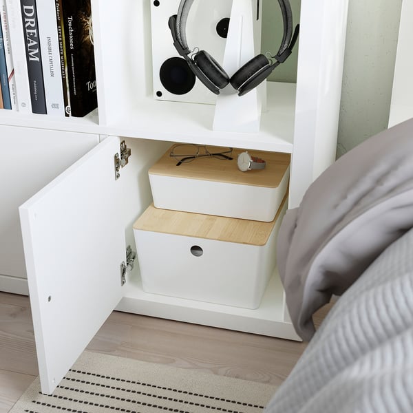 Bedside KALLAX shelf with boxes and headphones, showing storage and organisation.