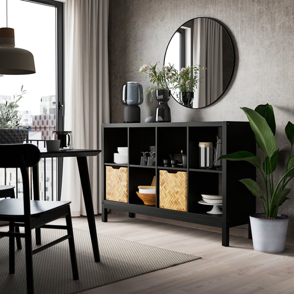 KALLAX black shelving with baskets, near window, surrounded by dining set and plants.