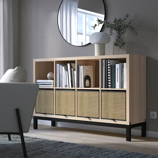 KALLAX honeycomb shelves with light wood, greenish plants, and white lamp; large, low, modern bookcase.