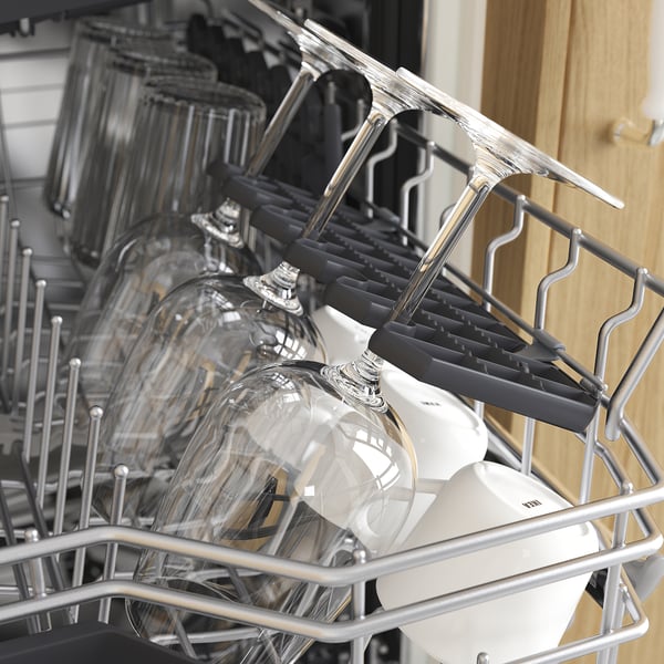 Dishwashers cutlery rack with foldable holders, seen in close-up, holding clear glasses and white items, demonstrating its versatile storage.