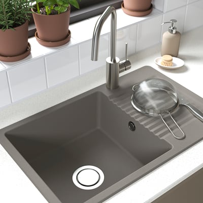 Black sink with stainless tap and strainer; plants nearby.
