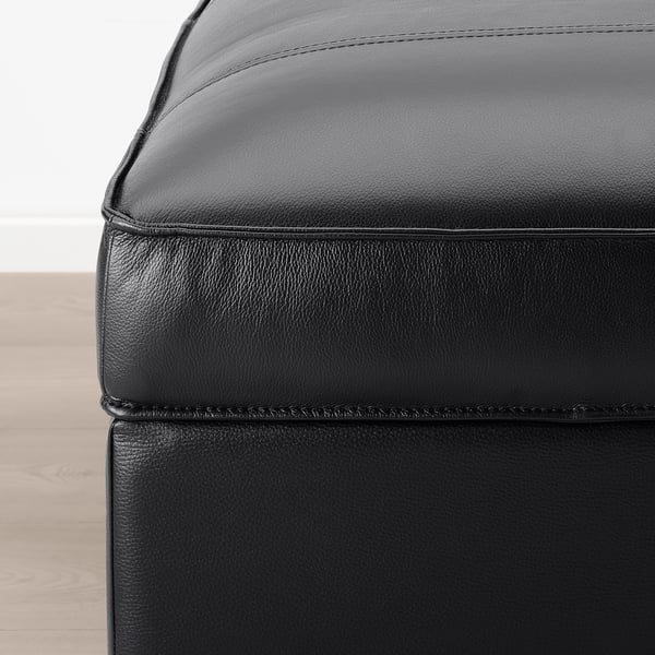 Close-up of black leather KIVIK footstool, showing smooth, high-quality grain and neat stitching.
