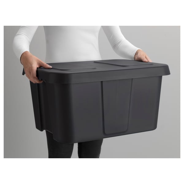 Person holding a large, dark grey, sturdy plastic storage box with snap-lock lid designed for outdoor use.