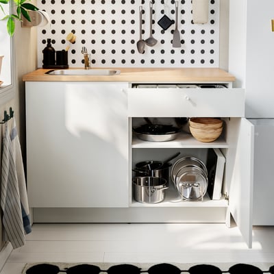 Modern kitchen setup featuring KNOXHULT unit with open drawer showing pots and pans, wooden countertop, and polka-dot patterned wall.