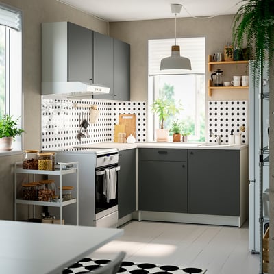 Modern l-shaped kitchen dark grey cabinets, sleek countertops, and open shelving with potted plants and coffee essentials.