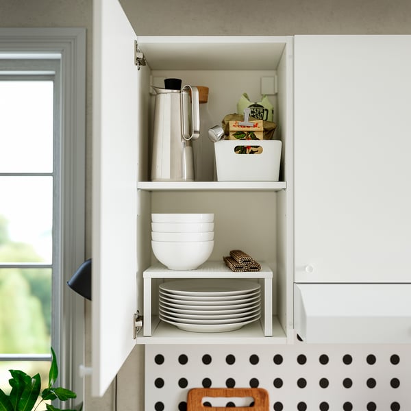 Open kitchen cabinet displaying bowls, plates, and kitchen items on shelves.