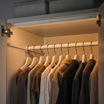 Modern closet with warm led lights. Slim, automatic sensor lights illuminate hangers and clothes.