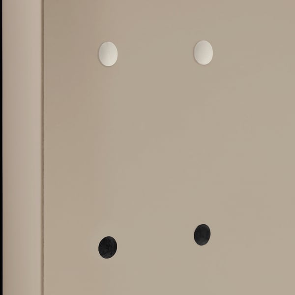 Four circular holes in a beige surface, two covered with white caps and two with black caps, showcasing furniture hole covers.