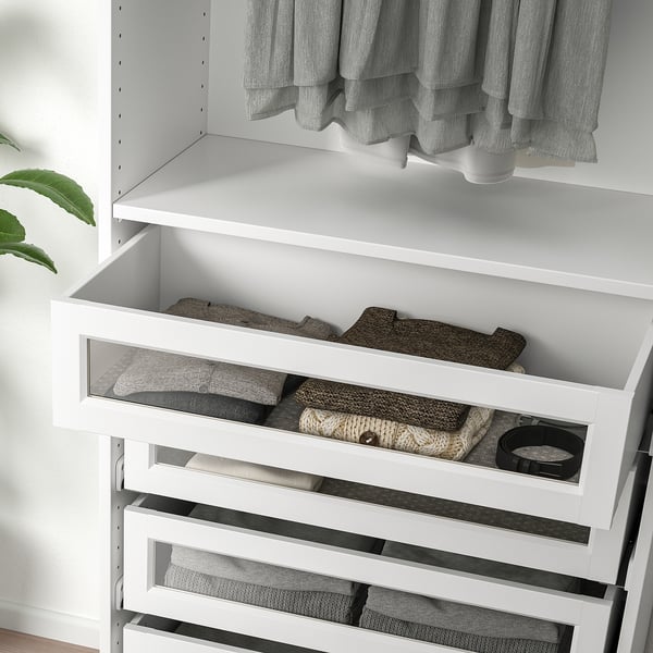 White wardrobe drawer with framed glass, showing neatly folded towels inside. Part of a pax wardrobe system.