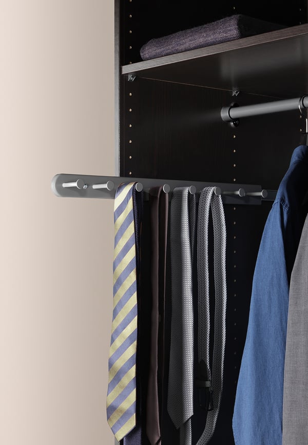KOMPLEMENT black closet organiser holds ties on metal rod, black background.