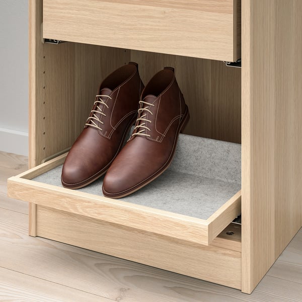 Pull-out tray in light wood wardrobe, holding brown leather shoes on felt mat.