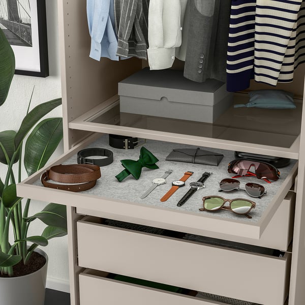 Open closet with clothes, drawer of accessories, and plant.