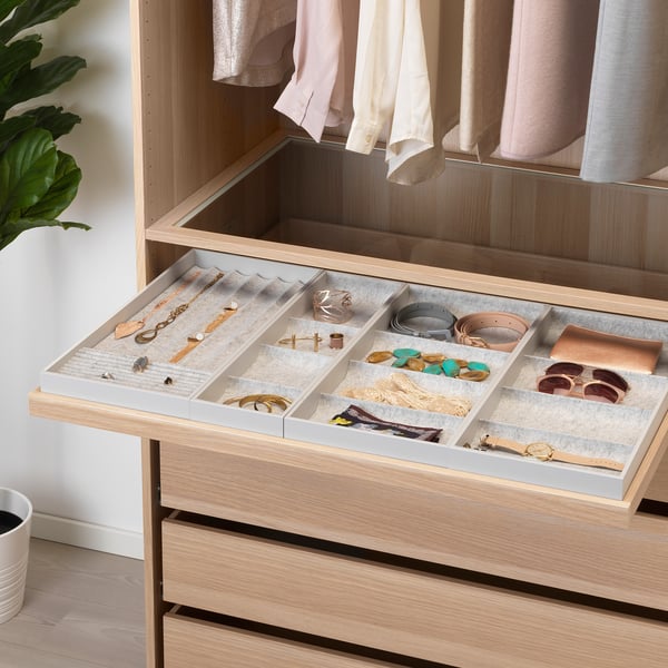 Organised drawer with compartments for jewellery and accessories in a well-lit closet.