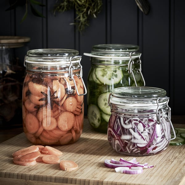 Three jars with pickled veggies on wooden table.