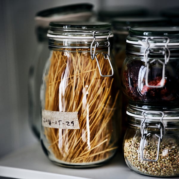 Three glass jars with metal clamps store dried noodles and seeds, sealed for freshness.