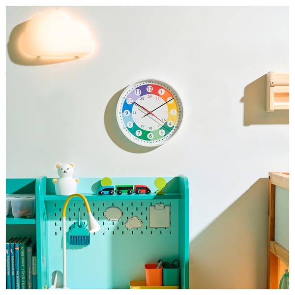 Colourful wall clock with numbers and a wall lamp, toys, and shelves.