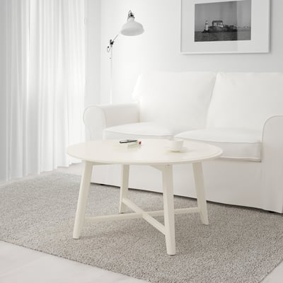 Small, white coffee table with round top and four legs. It holds a cup and coasters. Perfect for small spaces.